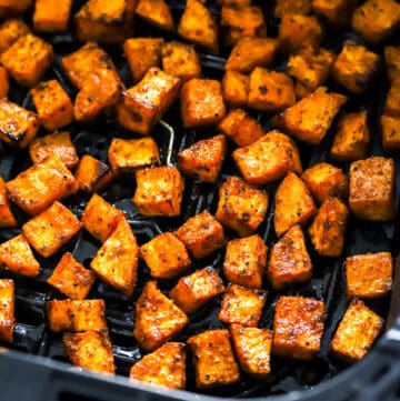 Cubed cooked air fryer sweet potato cubes in a black air fryer basket.