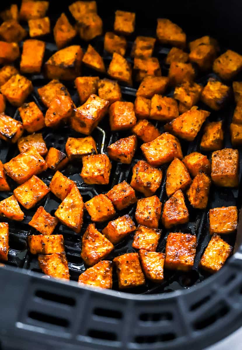 Cubed cooked air fryer sweet potato cubes in a black air fryer basket. 