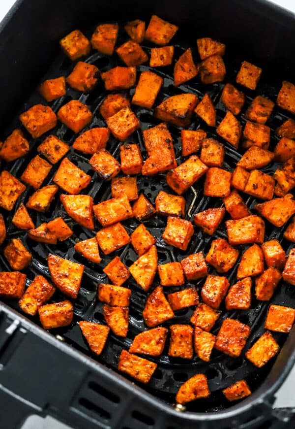 Cooked, roasted sweet potatoes in an air fryer basket.