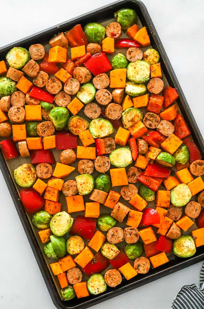 Chopped vegetables ad sausage on a baking sheet.
