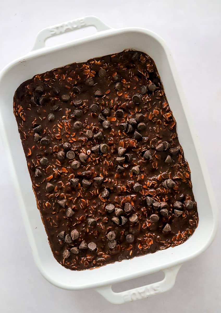 Pan of brownie oats with chocolate chips uncooked in a white baking dish.