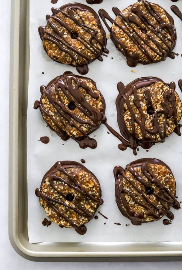 No bake Samoas cookies with chocolate drizzled on them on a lined baking sheet.