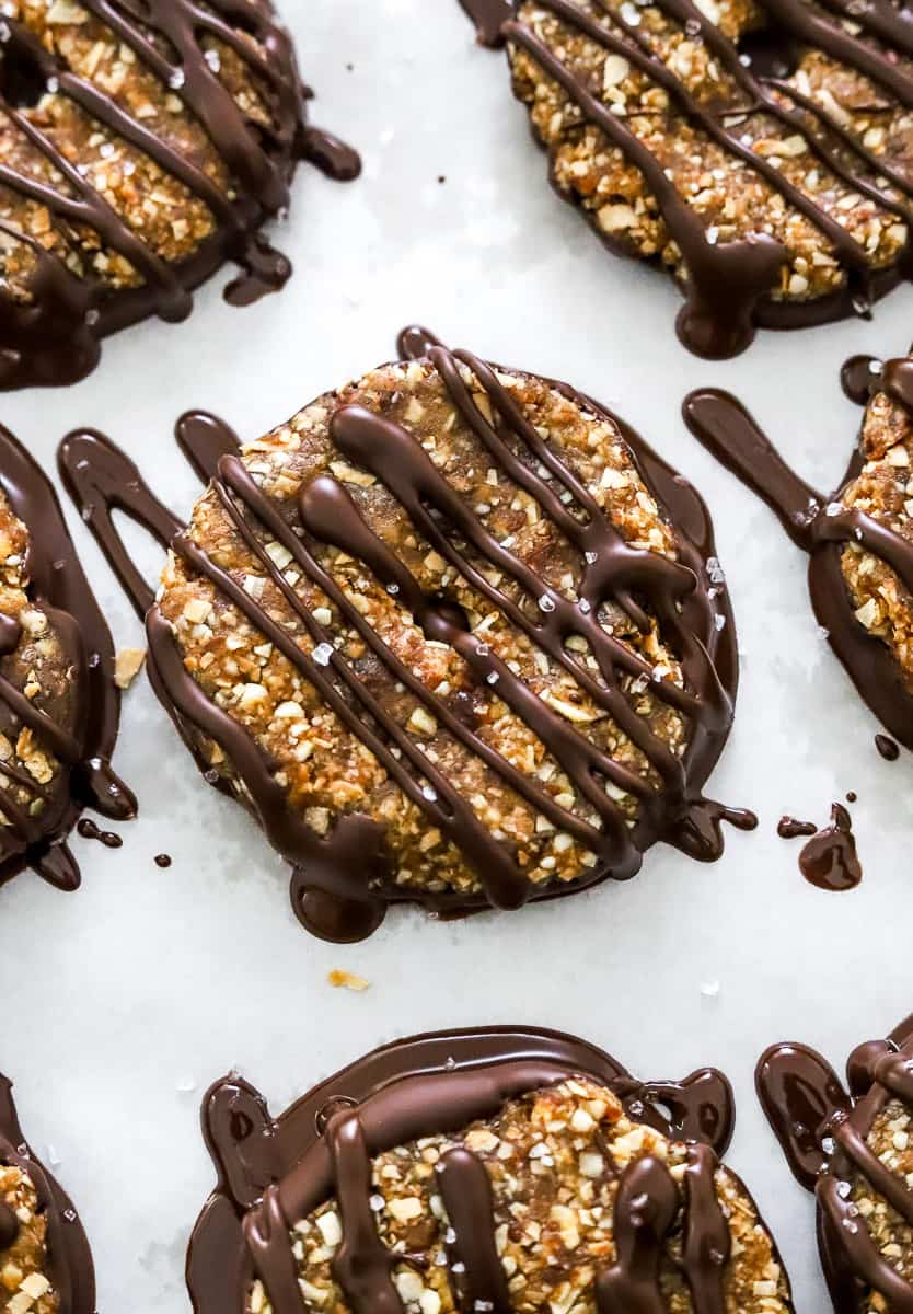 Samoas cookies drizzled with melted chocolate on the on a parchment paper lined baking sheet.