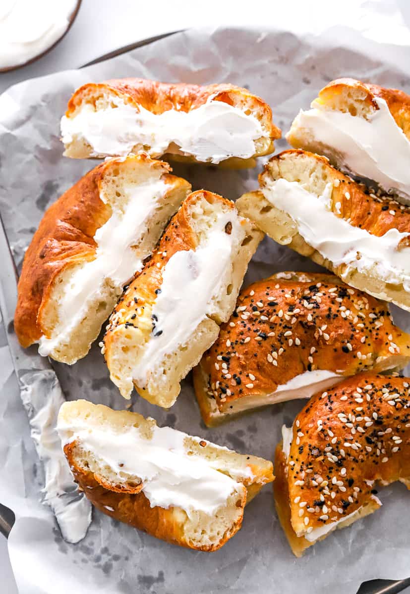 Bagel cream, cheese sandwiches sliced in half on a lined plate. 