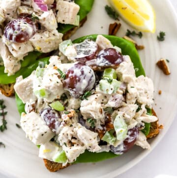 Healthy chicken salad on a piece of whole grain bread on a plate with another one behind it.