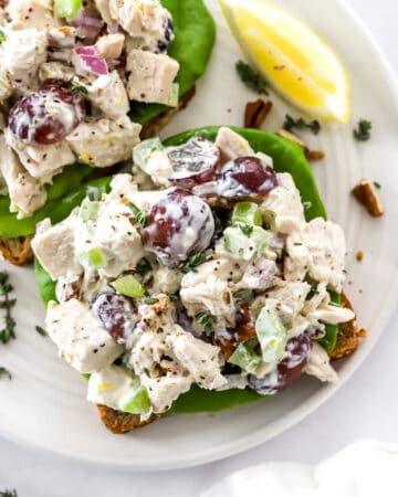 Healthy chicken salad on a piece of whole grain bread on a plate with another one behind it.