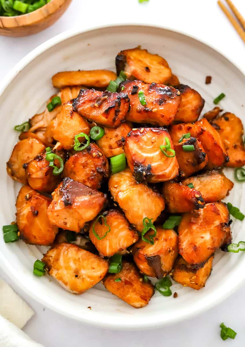 Bowl filled with air fryer crispy salmon bites with chopped scallion on them. 