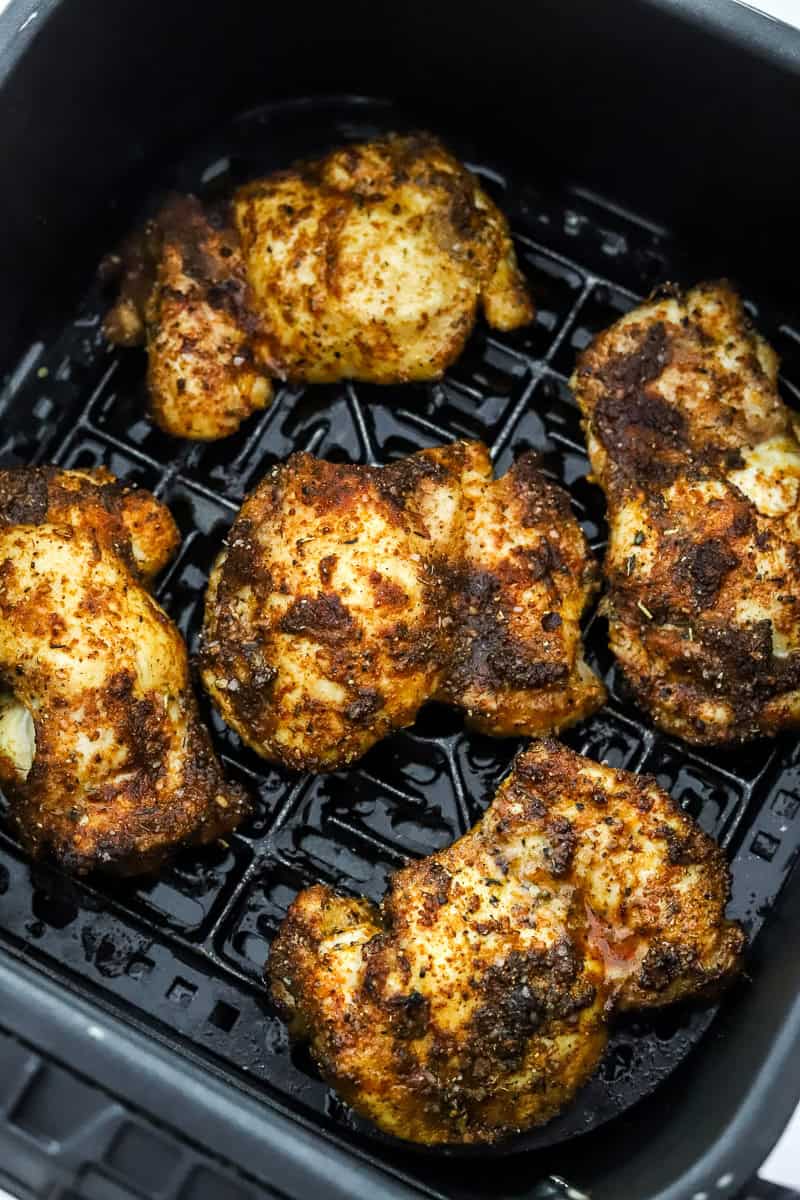 Boneless chicken thighs cooked in a black air fryer basket.