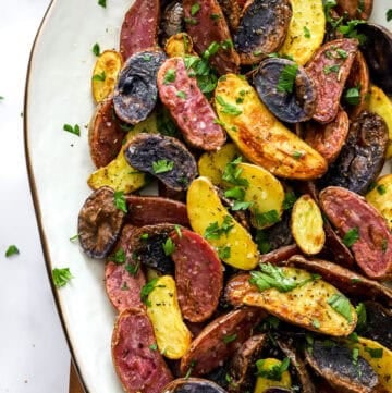 Multi coloured golden air fryer fingerling potatoes on a platter topped with parsley.