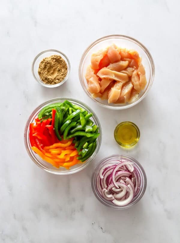 Ingredients for chicken and veggies fajitas in bowls.