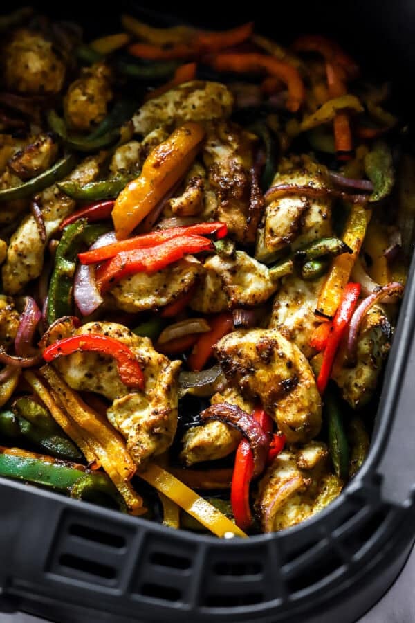 Cooked chicken and peppers in an air fryer basket.