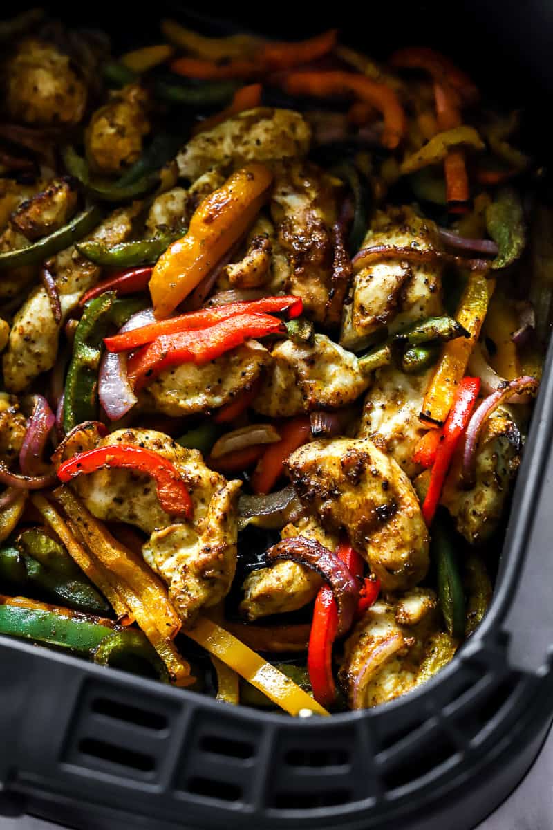 Cooked chicken and peppers in an air fryer basket.