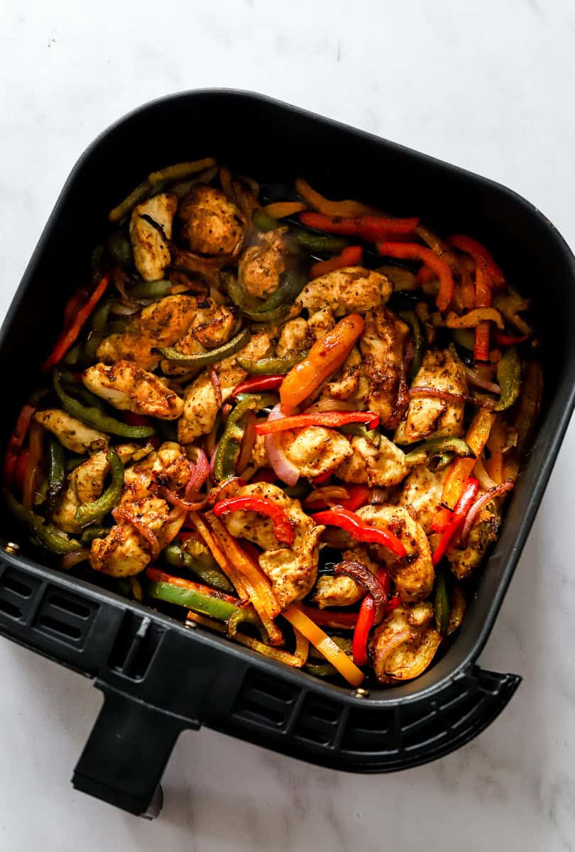 Cooked chicken fajitas in a black air fryer basket