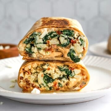 Egg white wrap with veggies filling cut on a plate.