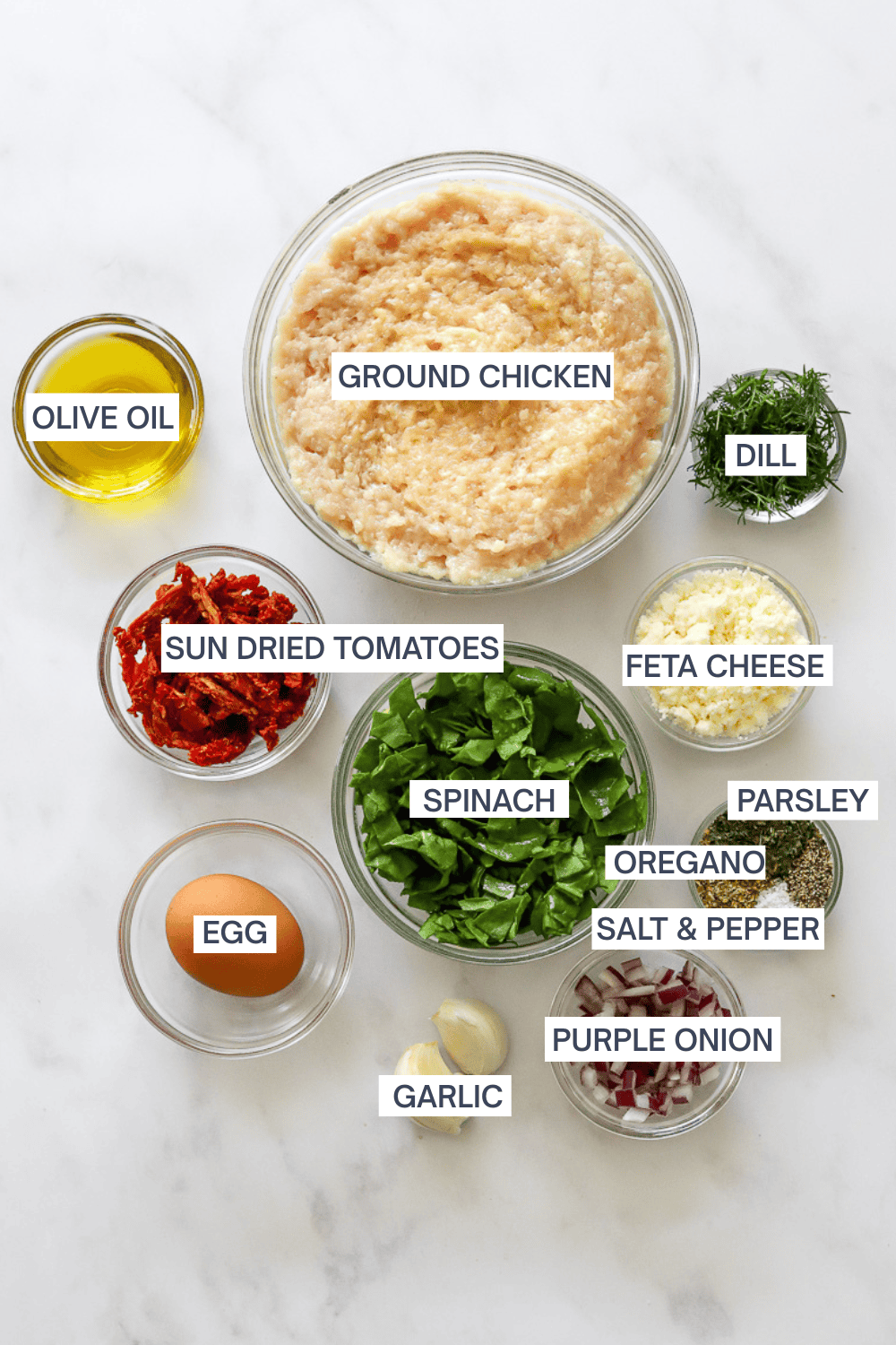 Ingredients for Greek chicken burgers in bowls with labels over each ingredient.