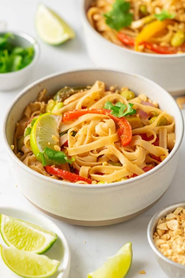 Vegetarian pad thai in a bowl with more around it.