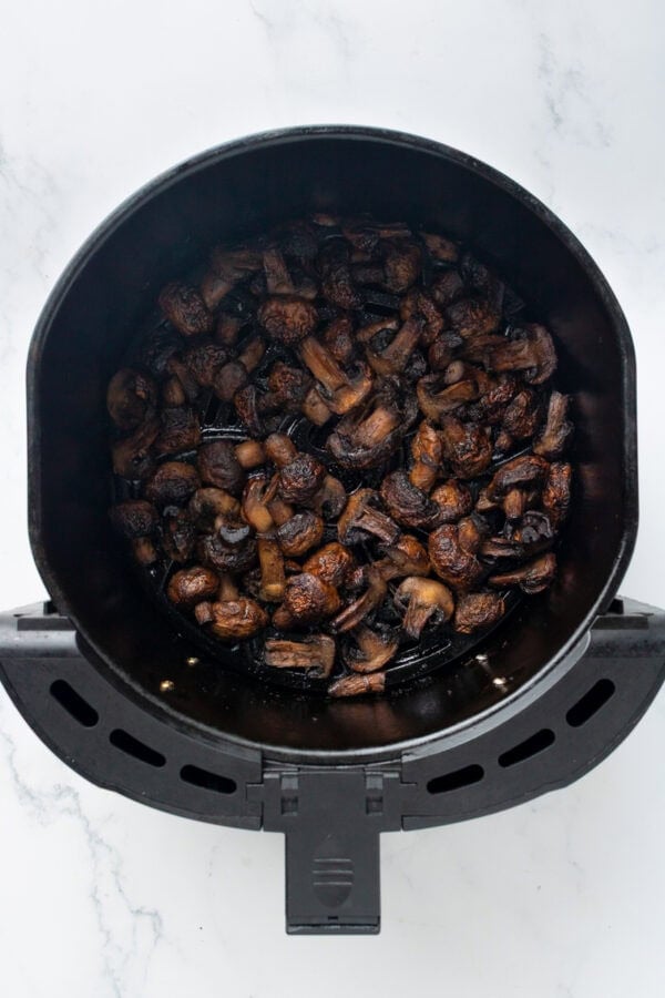 Cooked mushrooms in air fryer basket.