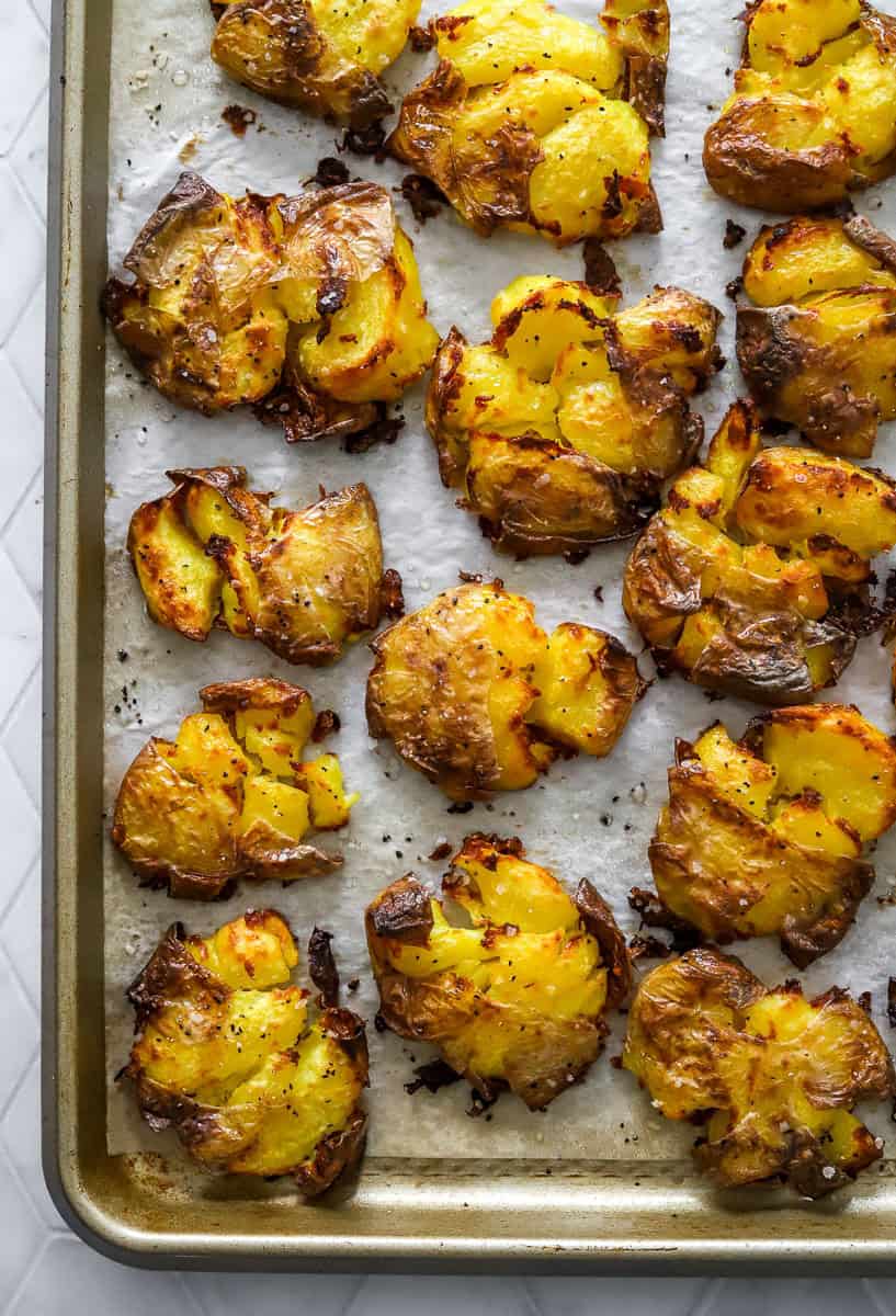 Crispy baked smashed potatoes on a lined baking sheet.