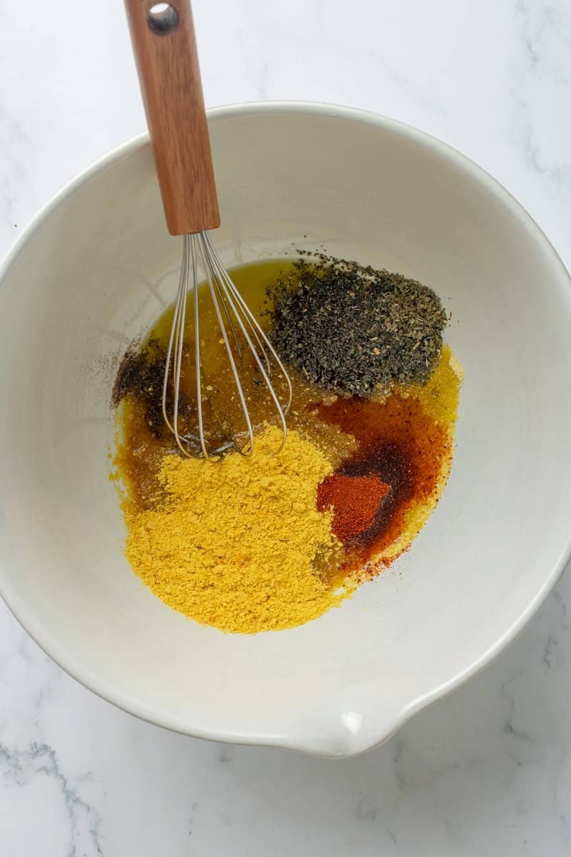 Seasoning in a white bowl with a whisk in it.