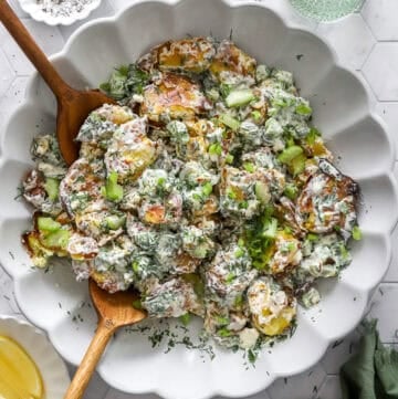 Crispy smashed potato salad in a serve bowl with more toppings in bowls around it.