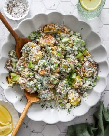 Crispy smashed potato salad in a serve bowl with more toppings in bowls around it.