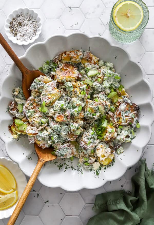 Crispy smashed potato salad in a serve bowl with more toppings in bowls around it.