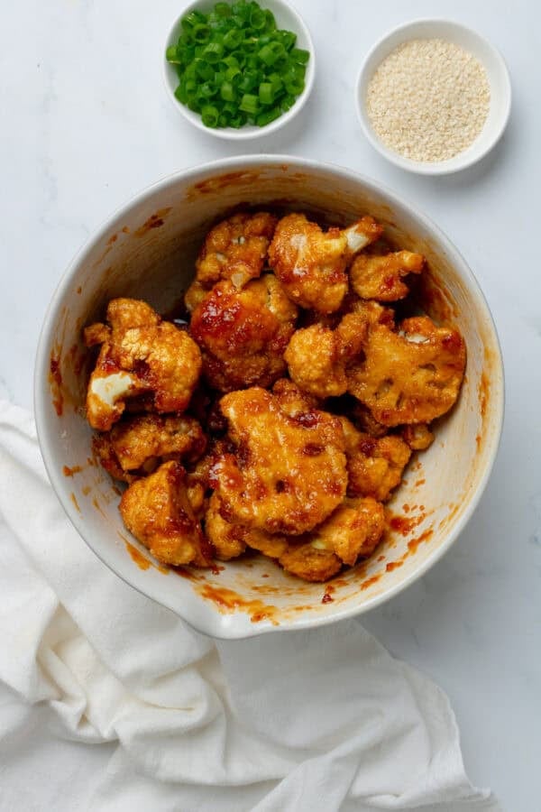Crispy baked cauliflower in bowl coated in sticky sauce.