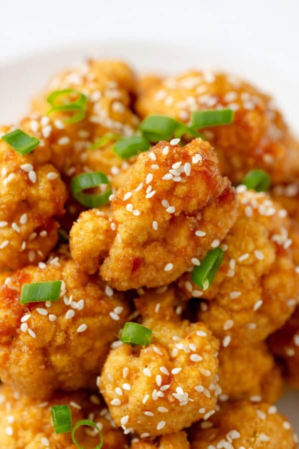 Baked breaded cauliflower wings with Asian sauce and sesame seeds on it.