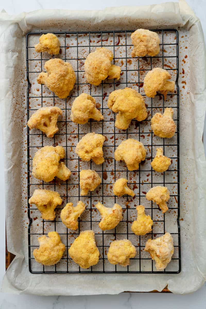 Baked cauliflower bites on lined baking pan.