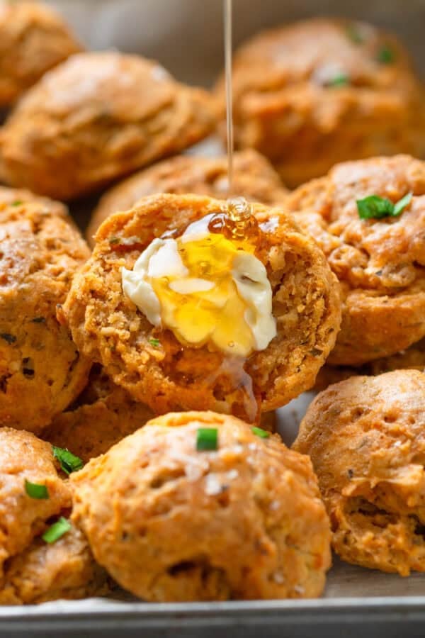 Pile of biscuits with butter and honey on one of them.