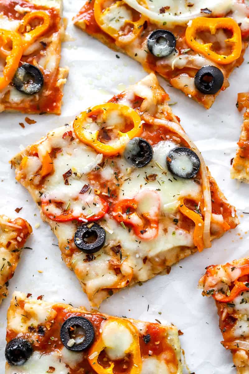 Ground chicken crust pizza with veggies cut into squares.