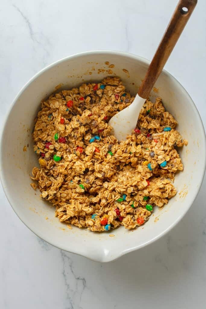 Mixed oat, energy bite mixture in a mixing bowl with a rubber spatula in it. 