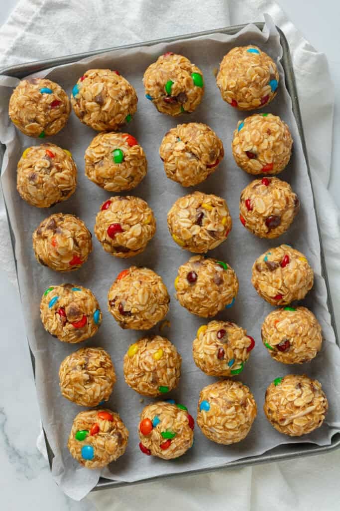 Assembled monster cookie balls on a parchment lined pan. 