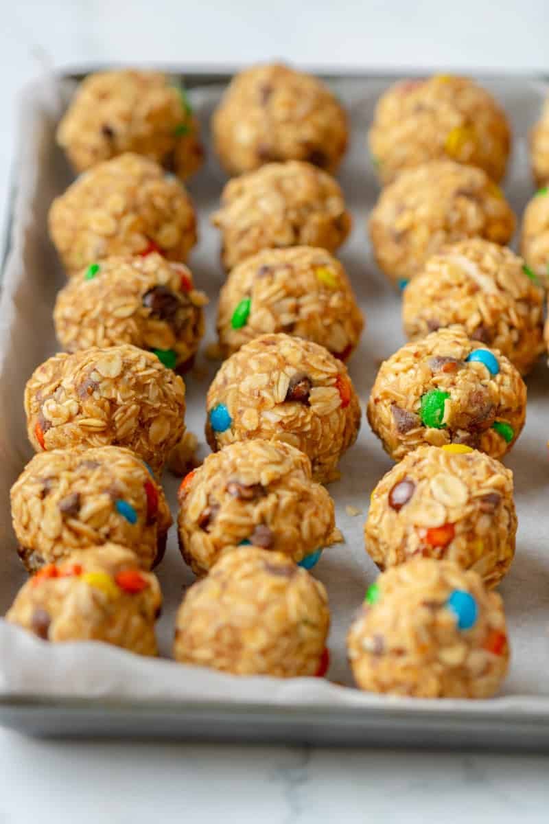 Lined baking pan filled with rolled oat and m&m energy bites. 