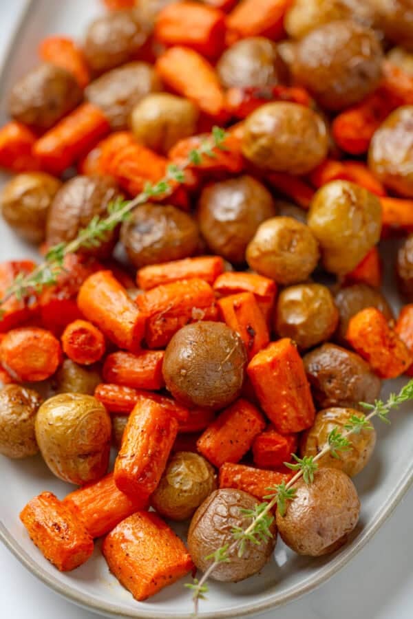 Herb and garlic roasted sheet pan carrots and potatoes on a plate.