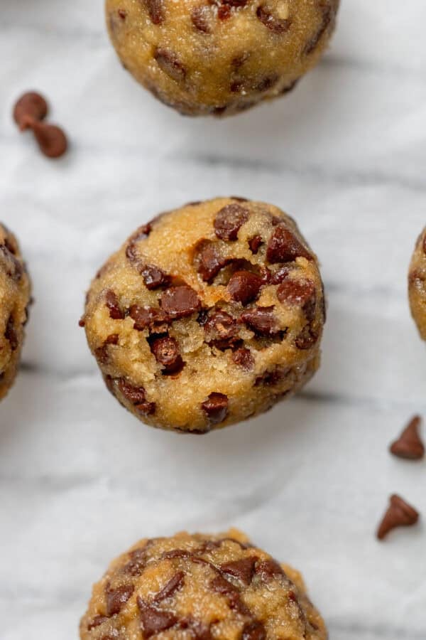 Rolled protein cookie dough balls with a bite taken out of one.