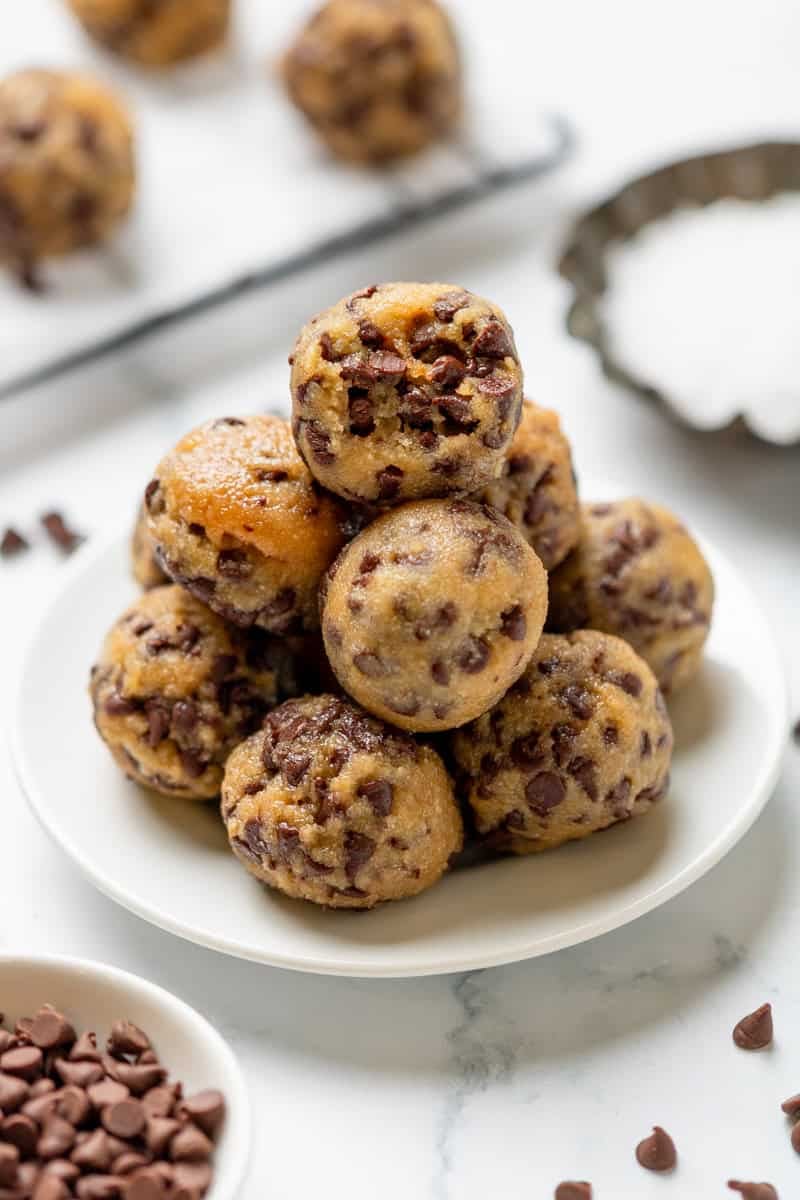 Plate filled with rolled cookie bites with chocolate chips with more behind it. 