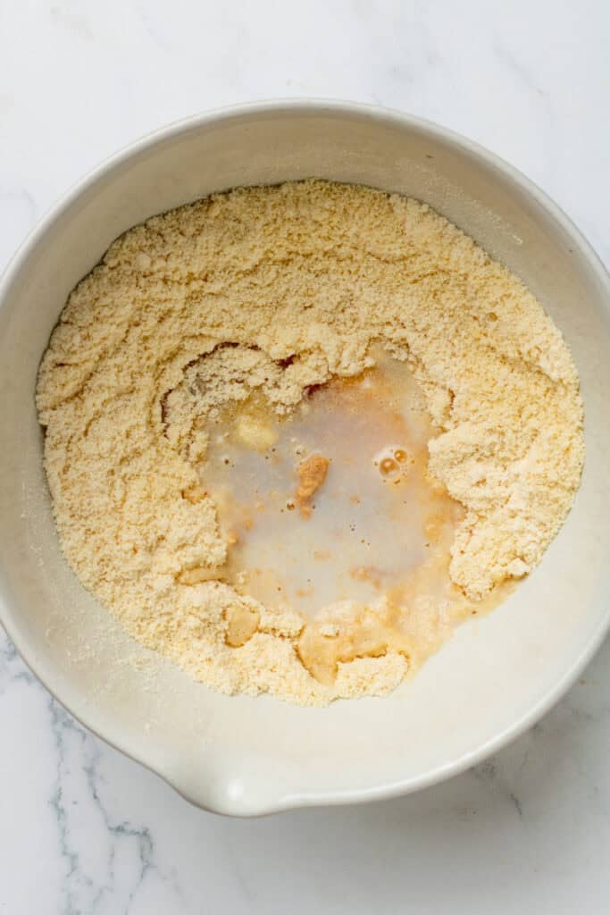 Almond flour, protein powder and milk in a mixing bowl before being mixed. 