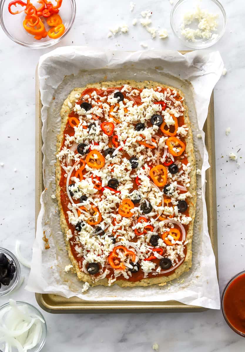 Cooked chicken crust pizza crust with toppings on it. 