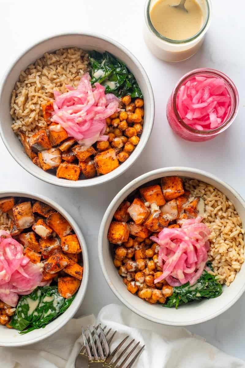Three bowls filled with roasted chickpeas and potato, spinach and rice.