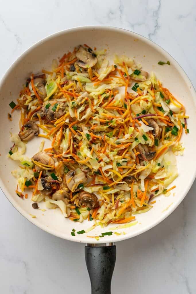 Cooked slaw mixture with garlic and ginger in pan.