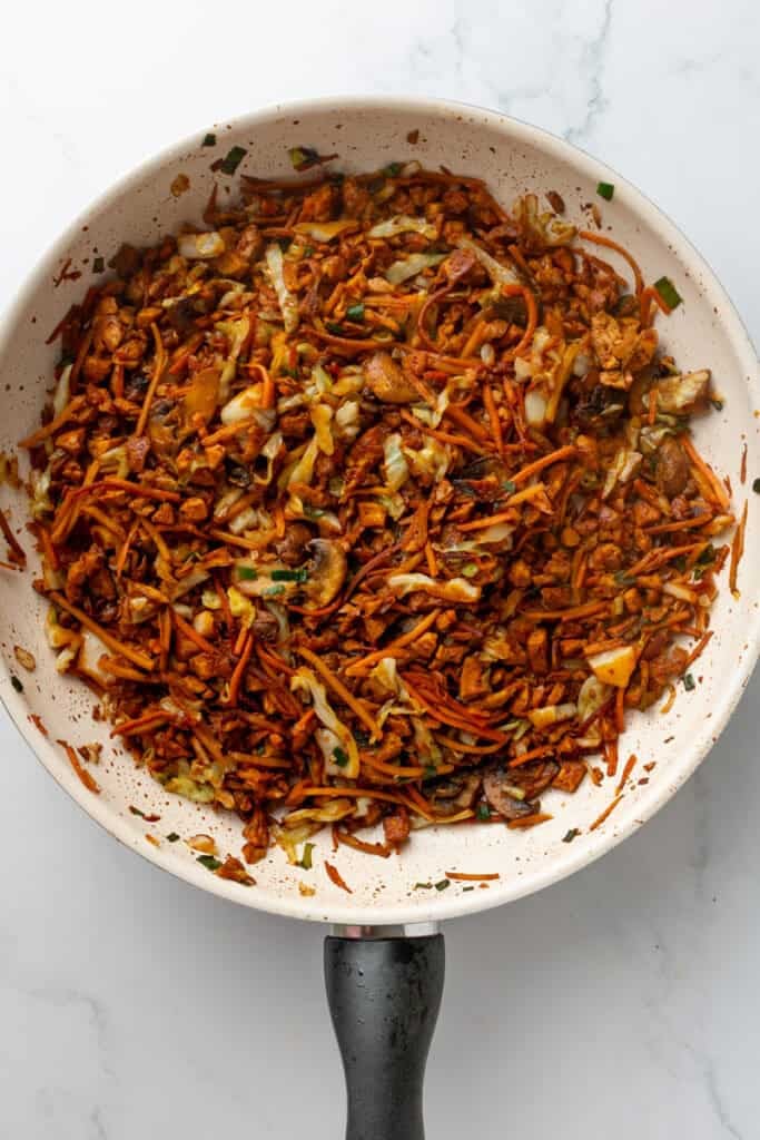 Tofu and veggie egg roll mixture cooked in pan.