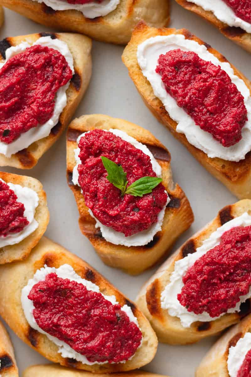 Grilled baguette slices with cheese and pink sauce on them.