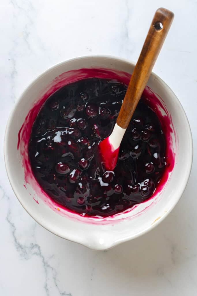 Blueberry parfait filling in a mixing bowl with a rubber spatula in it. 