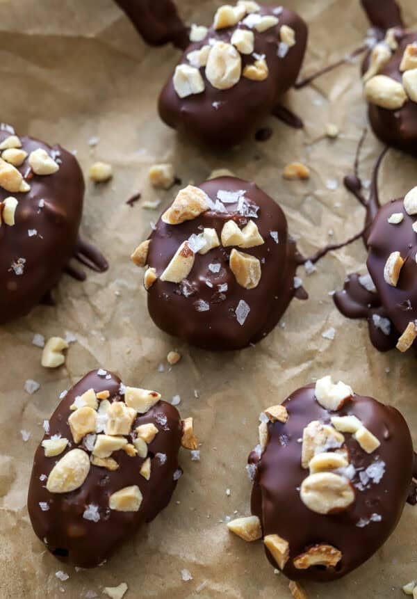 Date snickers with peanuts on top on a lined pan.