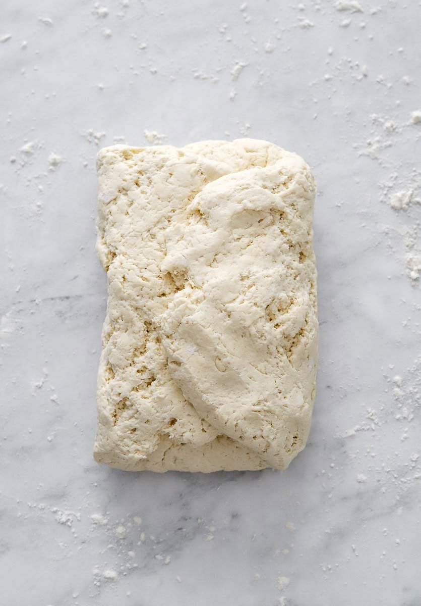 Folded biscuit dough on a floured surface.