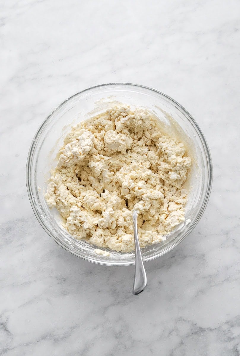 Greek yogurt biscuit dough in a bowl with a fork in the bowl.