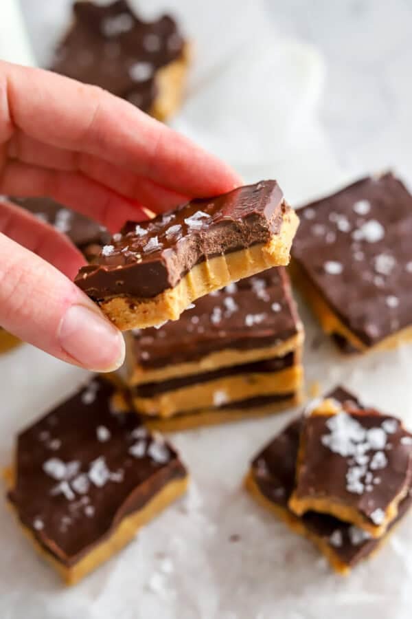 Hand holding chocolate nut butter bar with more behind it.