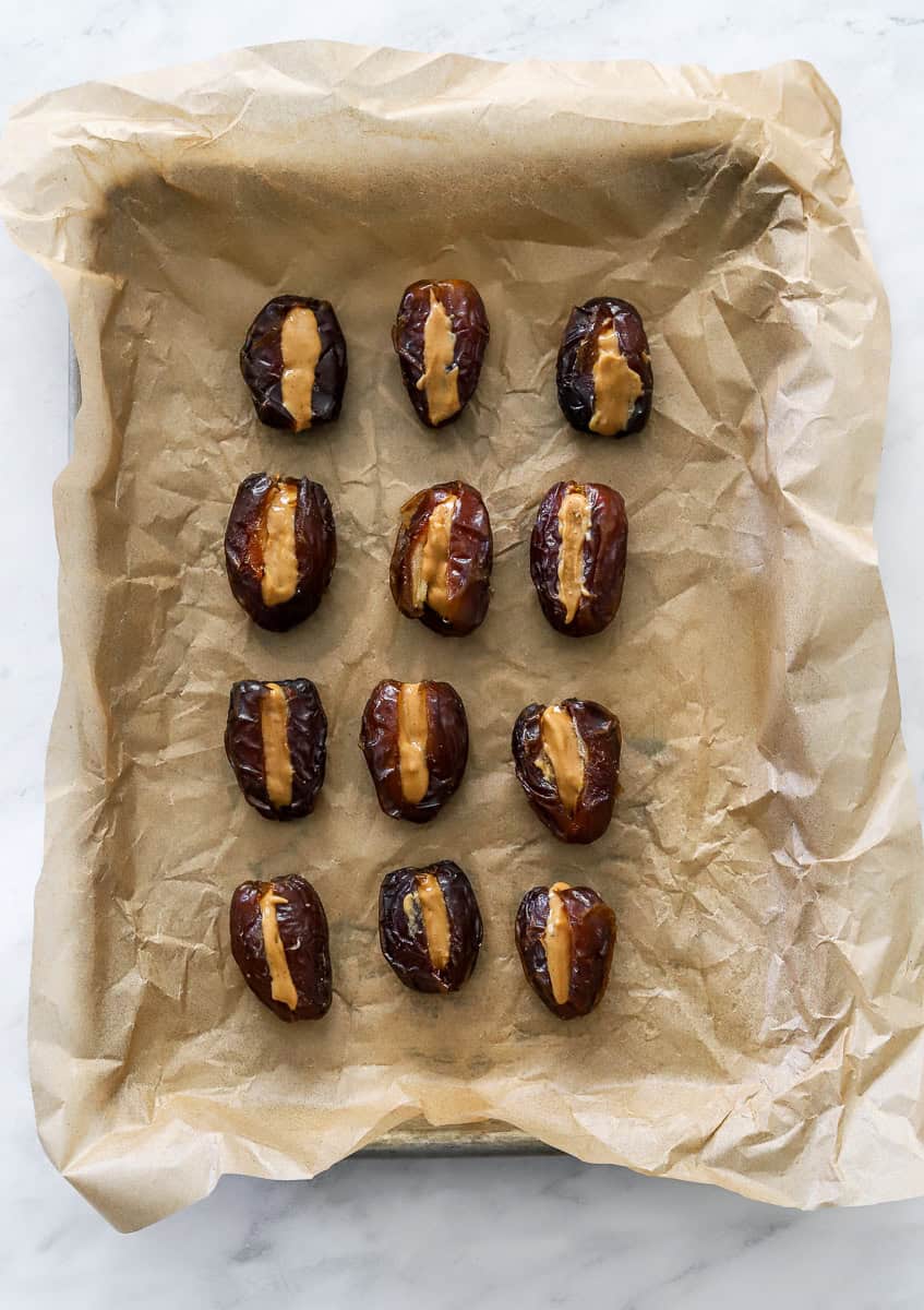 Peanut butter filled dates on a lined pan.