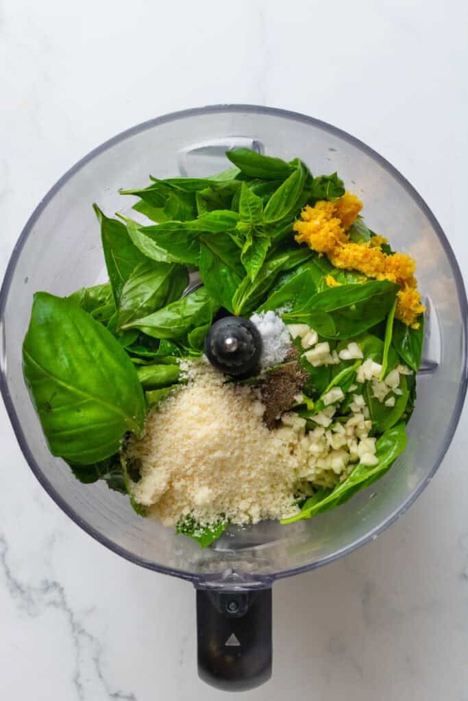 Pesto ingredients in a food processor before being blended.